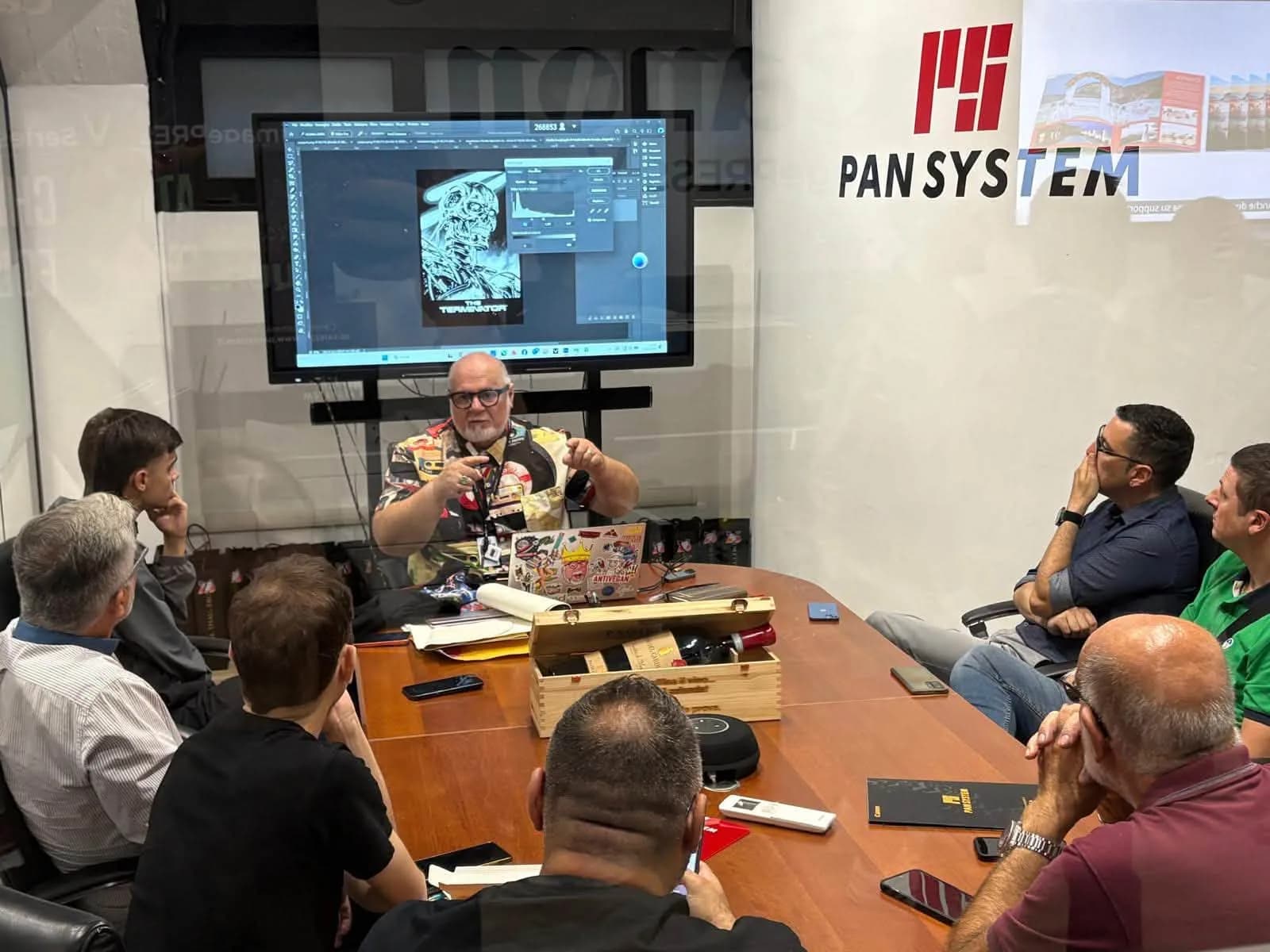 Dimostrazione grafica su schermo e partecipanti intorno al tavolo