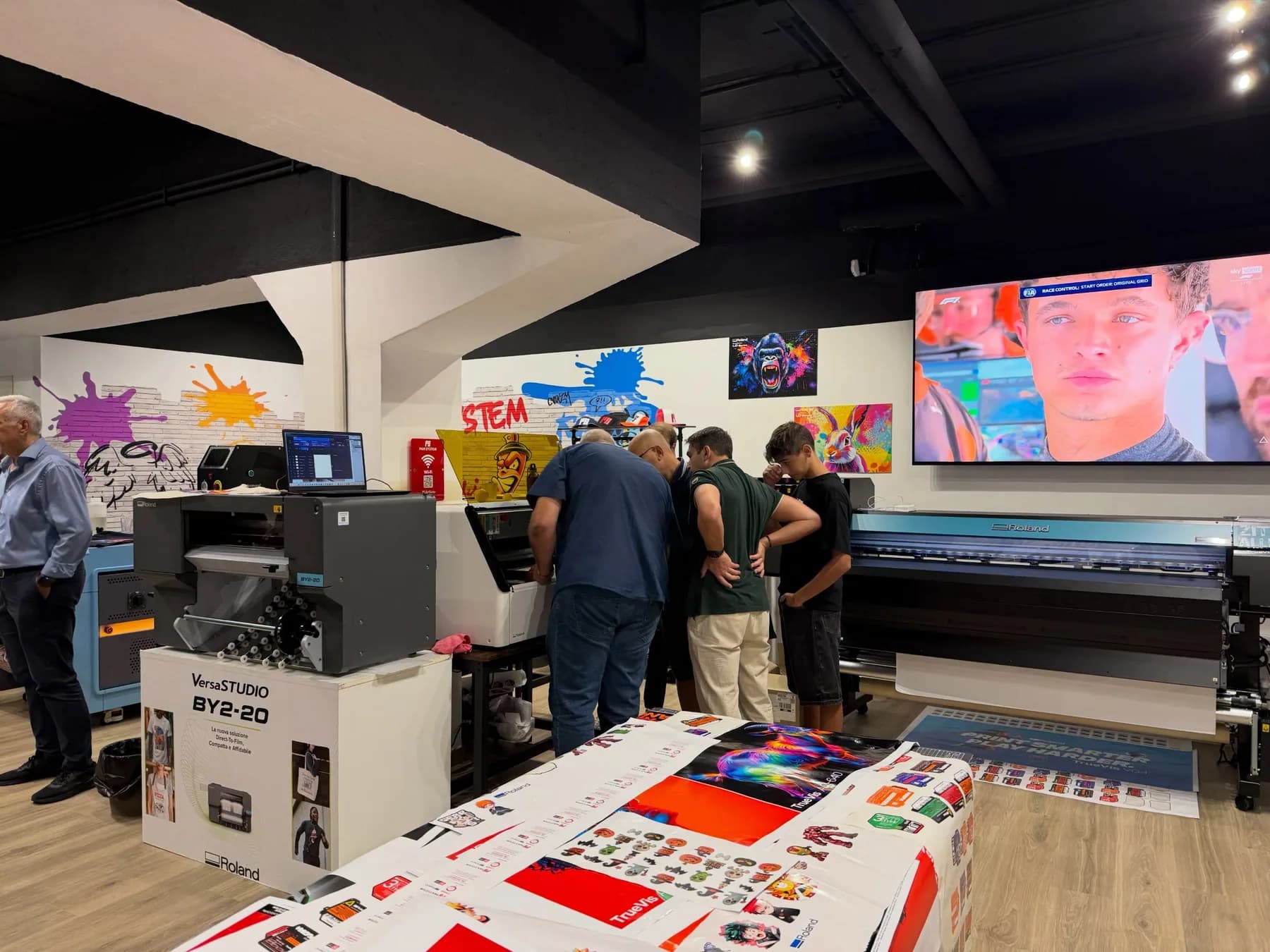 Grafica stampata in primo piano e partecipanti davanti alle tecnologie